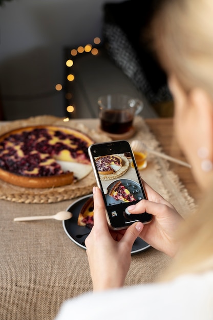 Foto mani femminili che scattano foto di una fetta di torta di ciliegie