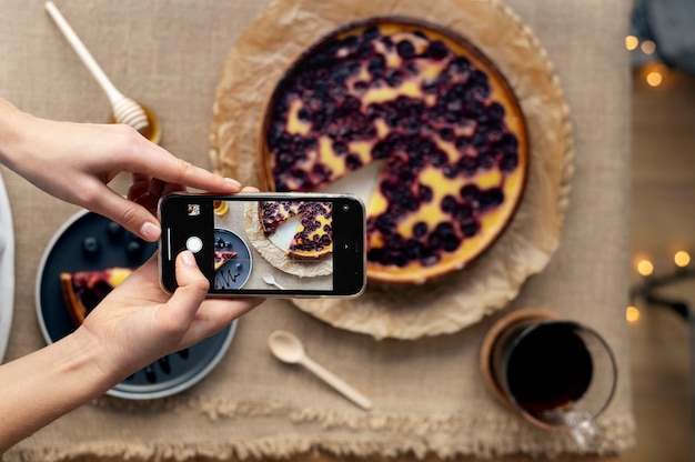 Foto mani femminili che scattano foto di una fetta di torta di ciliegie