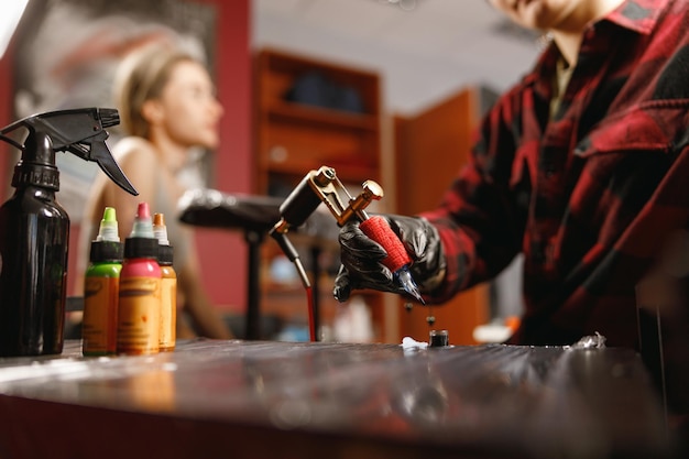 Female hands of tattoo artist holding tattoo machine