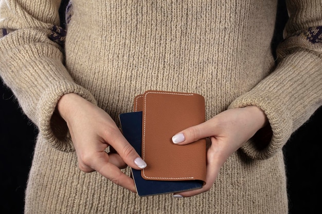 Nelle mani delle donne c'è una borsa marrone e un passaporto