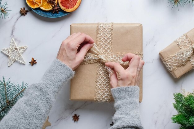 여성의 손은 크리스마스 선물이 있는 상자에 활을 묶습니다.