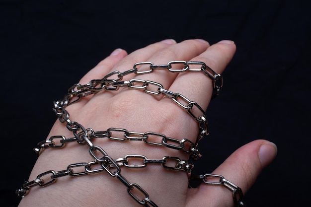 Female hands tied by metallic chain