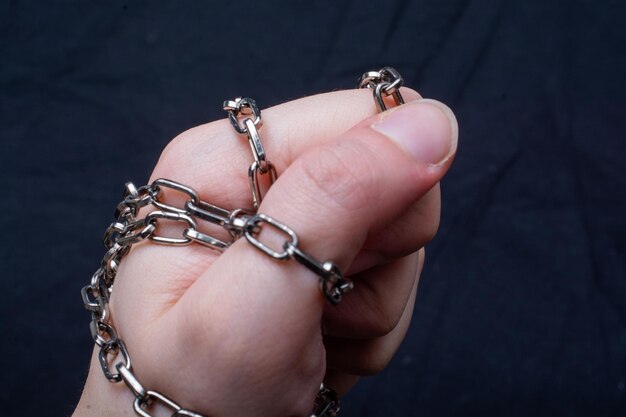 Female hands tied by metallic chain