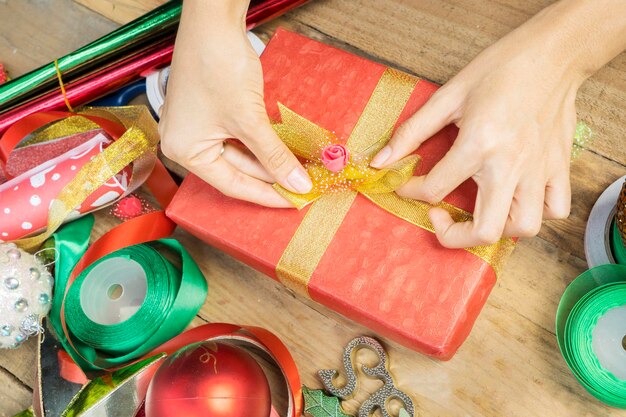 Foto mani femminili che legano un nodo su una scatola di regali di natale