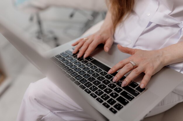 Female hands type text on laptop keyboard