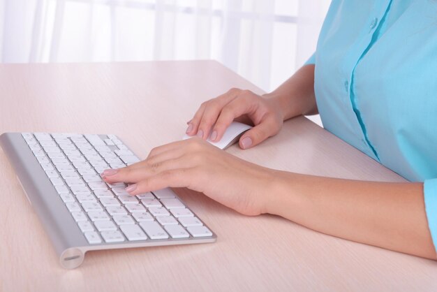 Female hands typing on keyboard on light background