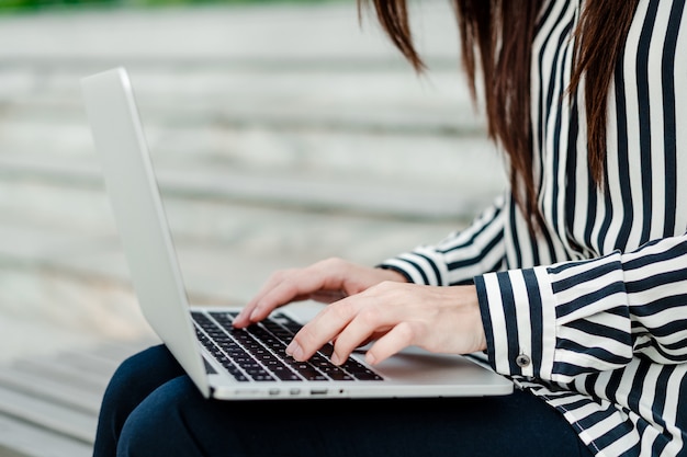 Female hands typing on laptop outdoors