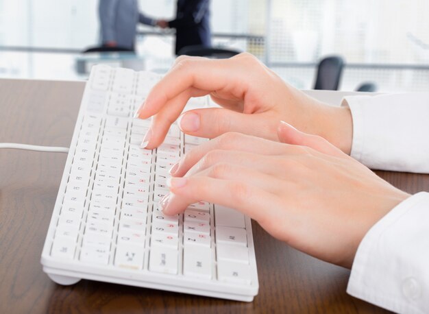 Female hands typing on white computer keyboard in office