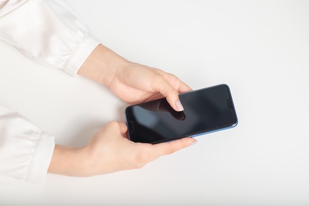 Le mani femminili usano il telefono al tavolo