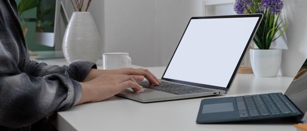 Female hands using mock-up laptop on home office desk