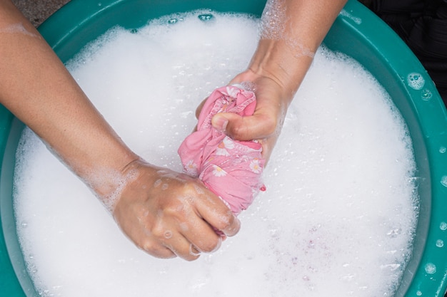 Photo female hands wash clothing by hand with detergent in basin.