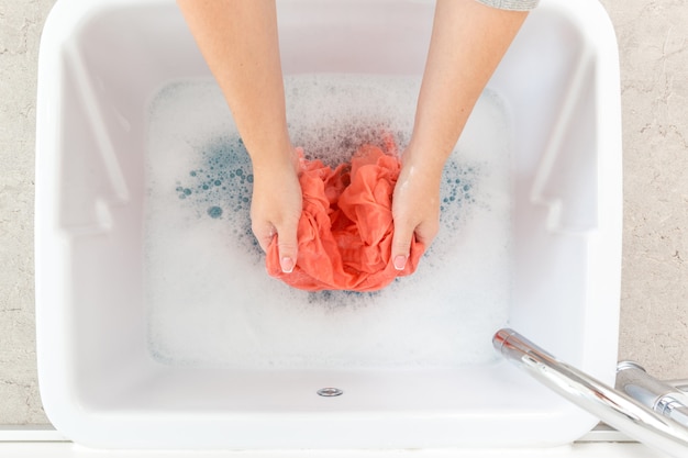 Female hands washing color clothes in sink