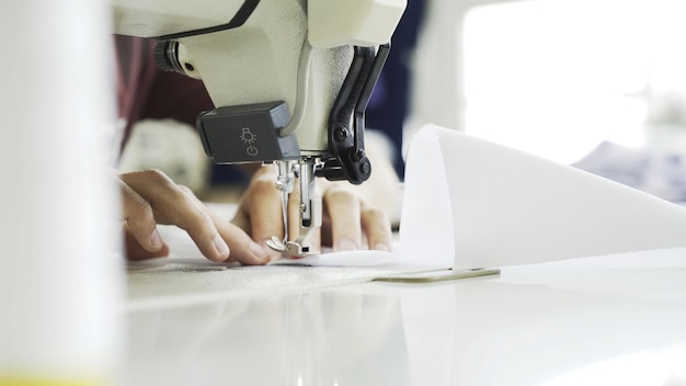 Female hands on white sewing machine top view shot