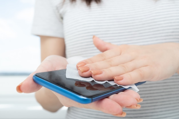 female hands wipe smartphone with antibacterial wipe