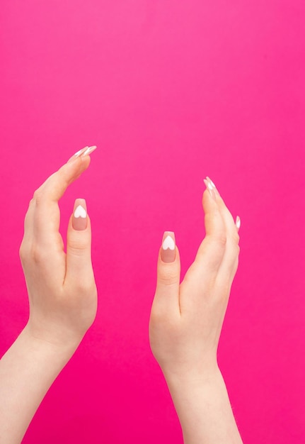 Female hands with beautiful long nails with  manicure with  heart pattern on pink background