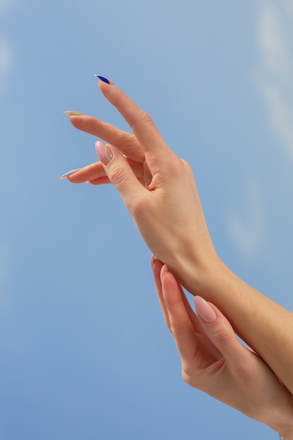 Female hands with beautiful manicure on a blue sky background