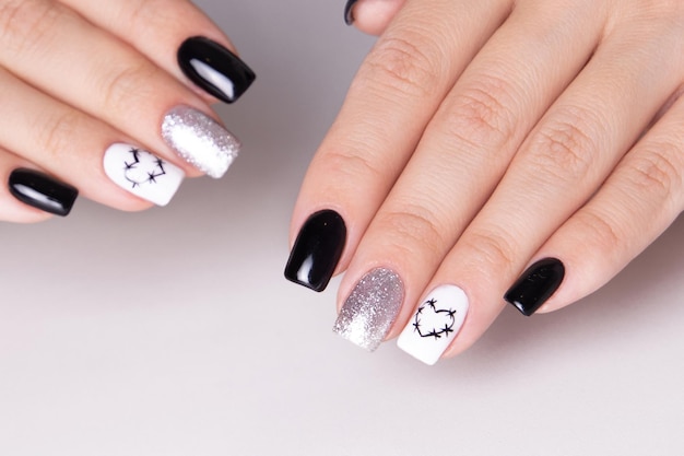 Female hands with black manicure nails, hearts design