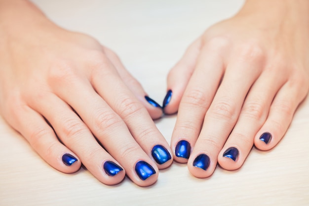 Женские руки с синим лаком для ногтей, крупным планом
