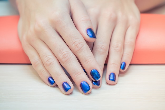 Женские руки с синим лаком для ногтей, крупным планом
