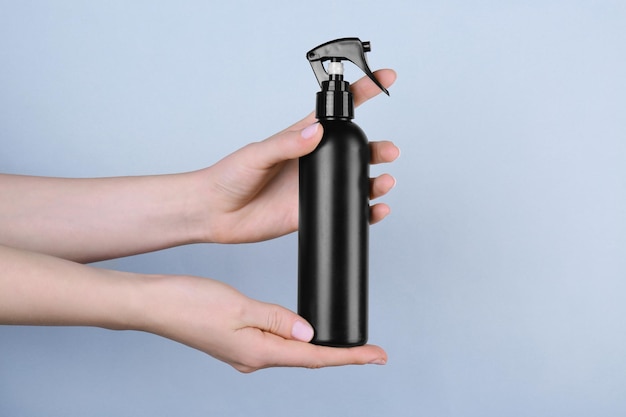 Female hands with bottle of cosmetic product for shower on color background