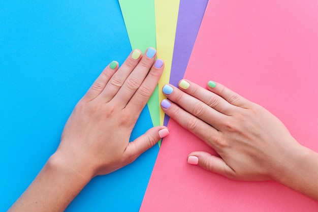 Mani femminili con colori vivaci su uno sfondo colorato