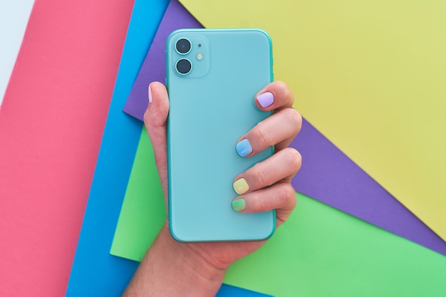 Female hands with bright colors holding a phone