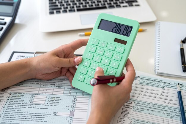 Female hands with calculator above 1040 tax form