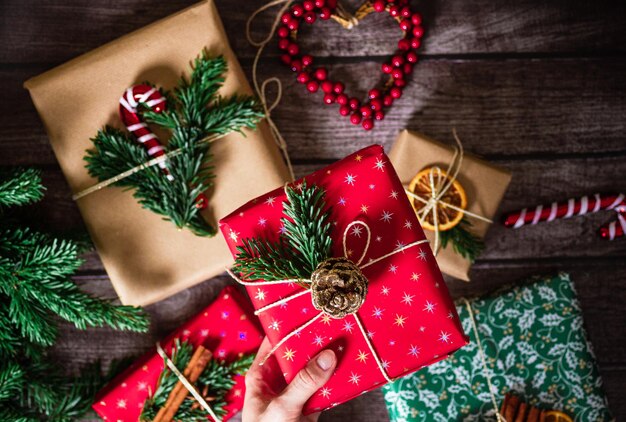 사진 크리스마스 선물과 함께 여성 손 새해 상자 크래프트 빨간 녹색 종이 장식과 소나무 가지