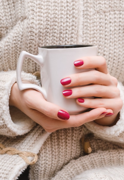 Female hands with dark pink nail design.