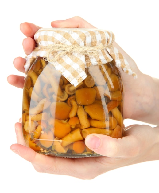 Female hands with delicious marinated mushrooms in glass jars isolated on white