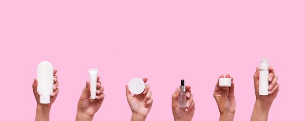 Female hands with different cosmetic products in container and bottles on pink color background