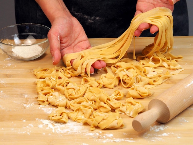 Female hands with dough for noodles and rolling pin
