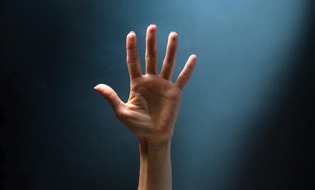 言葉のないジェスチャーコミュニケーションの青い背景の概念に指を上げて女性の手