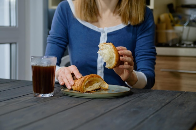 Mani femminili con il primo piano del croissant appena sfornato