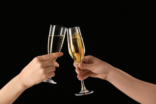 Female hands with glasses of champagne on dark background