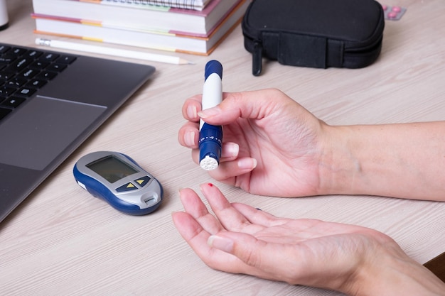 Photo female hands with a glucometer at the desk the lifestyle of a person with diabetes measuring the level of glucose in the blood