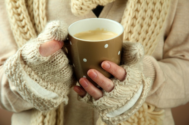 Mani femminili con bevanda calda, primo piano