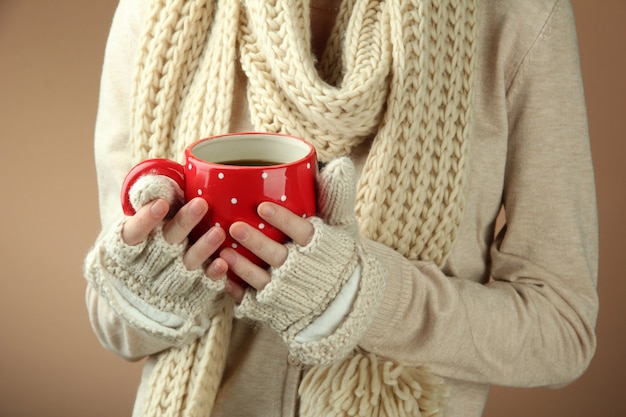 Female hands with hot drink, on color background