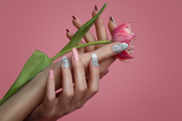 Mani femminili con unghie art design e fiore di primavera