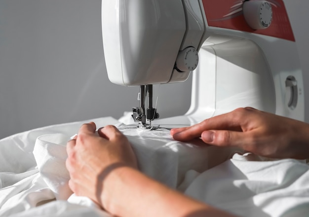 Female hands with natural cotton cloth working at sewing machine small sewing business concept