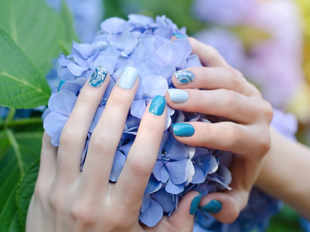 Female hands with a nice manicure on a blue flower