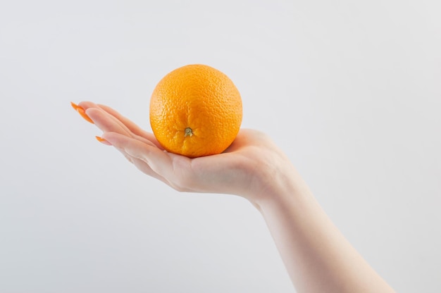 Female hands with orange on white background