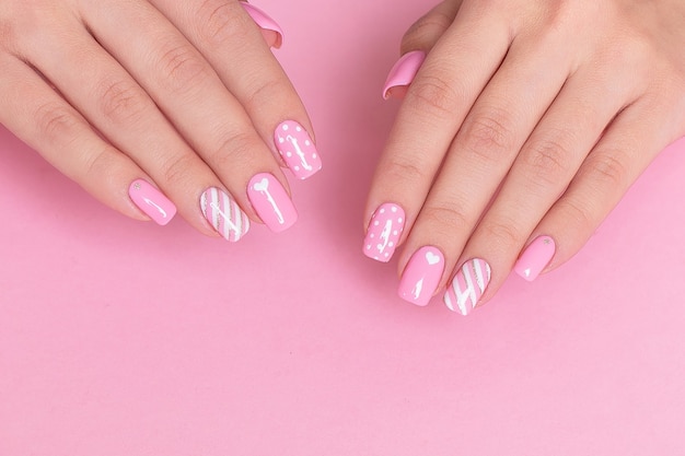 Female hands with pink manicure nails and Valentine's day design