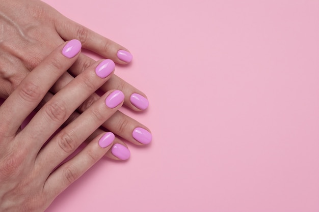 Female hands with pink nail polish, glamorous manicure.