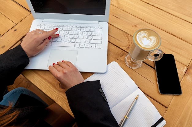 Female hands with red manicure on the background of a white laptop