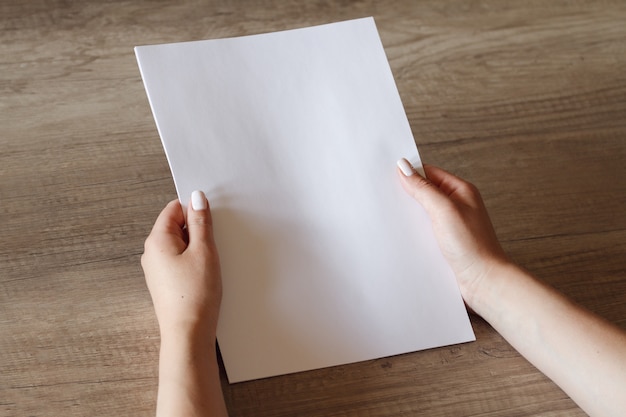 Female hands with a sheet of paper.