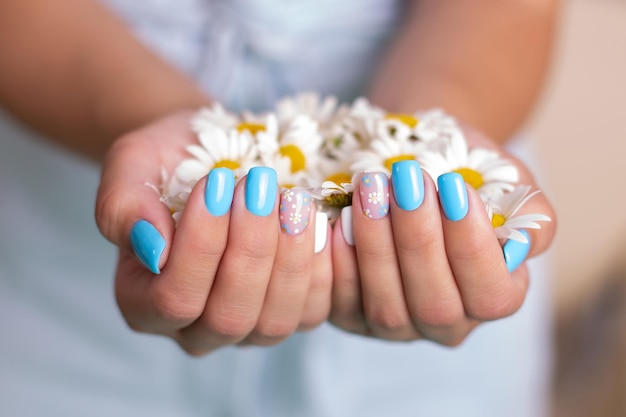 Female hands with summer manicure nails decorated with camomile flowers