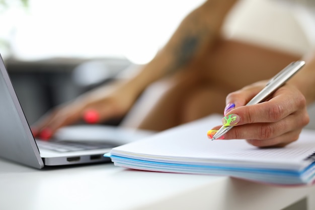 Female hands with summer manicure write in a notebook closeup a woman looks for information in