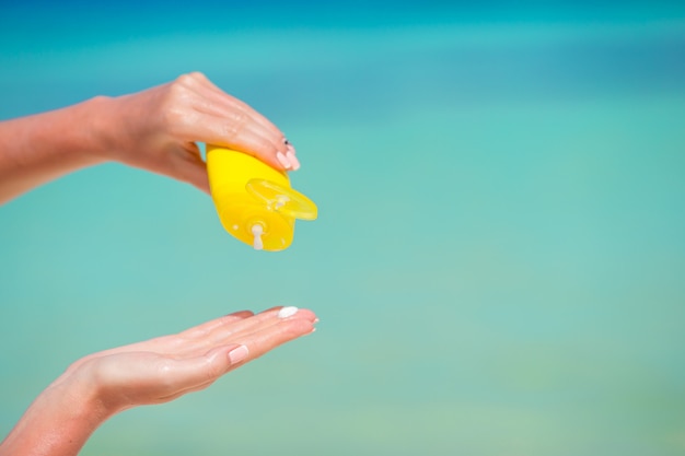 Female hands with suncream bottle blue sea