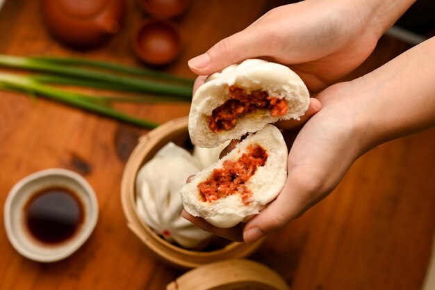 Photo above female hands with a tasty chinese steamed pork bbq buns